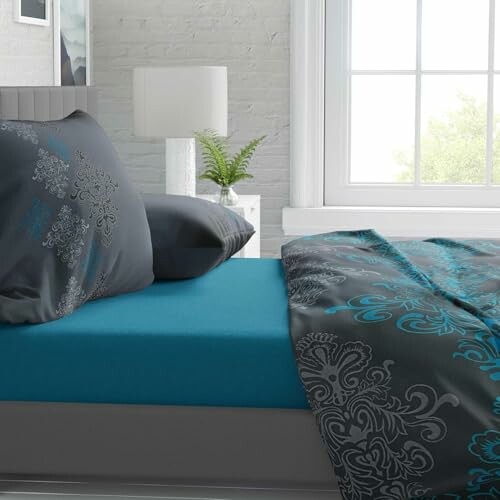 Modernes Schlafzimmer mit blauer Bettwäsche und dekorativen Kissen.